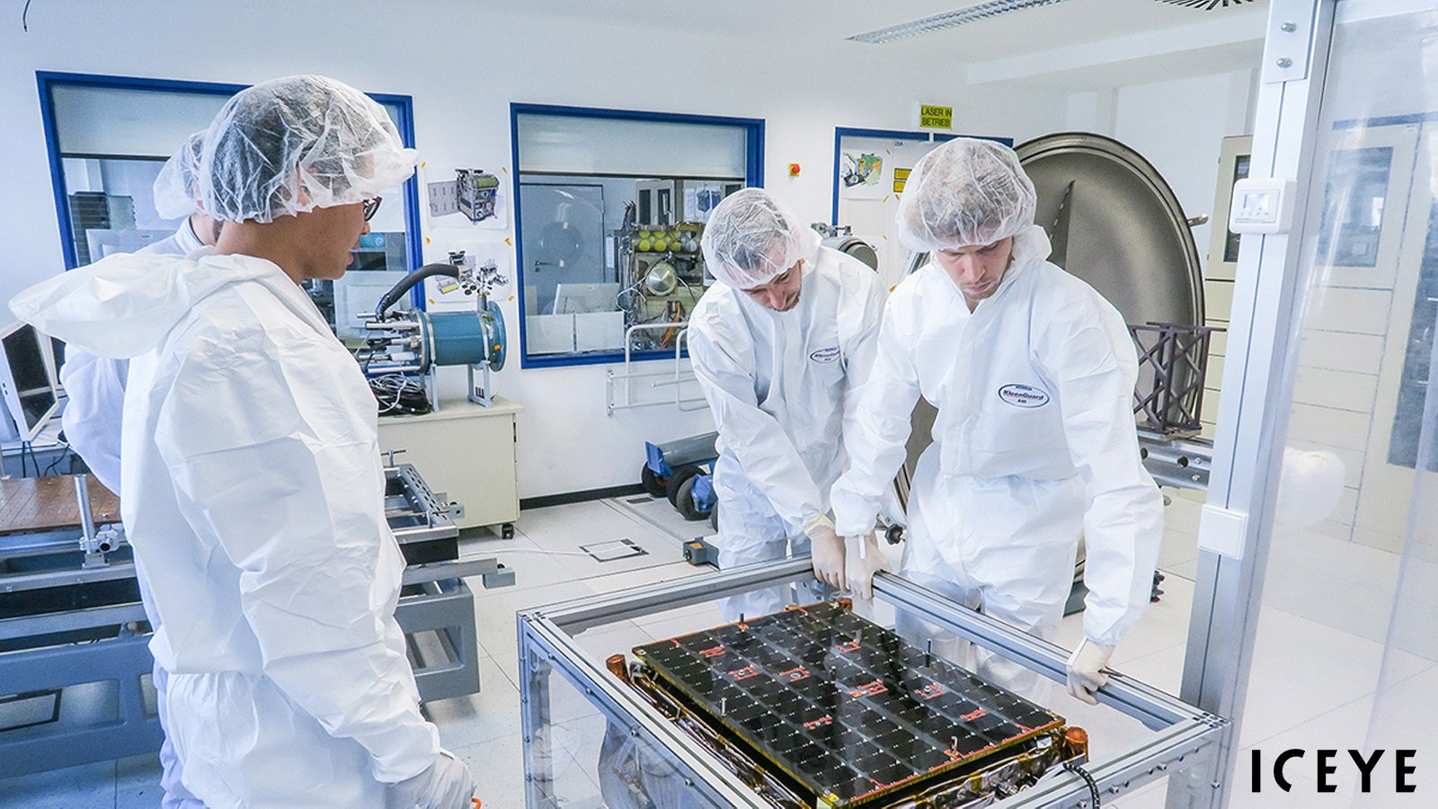 ICEYE specialists inspecting an ICEYE SAR satellite in a clean room.